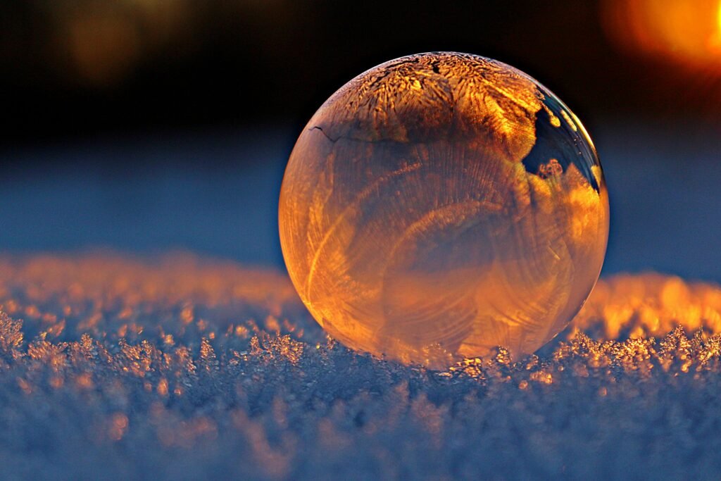 pexels-photo-302743-302743 Close-up shot of a frozen bubble with warm reflections resting on a snowy surface at twilight.