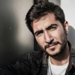 Close-up portrait of a confident man with a beard outdoors, embracing natural light.