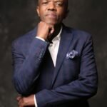 Stylish man in a blue suit posing confidently in a studio portrait.