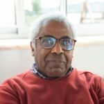 Close-up portrait of a senior man wearing glasses, indoors with natural light.